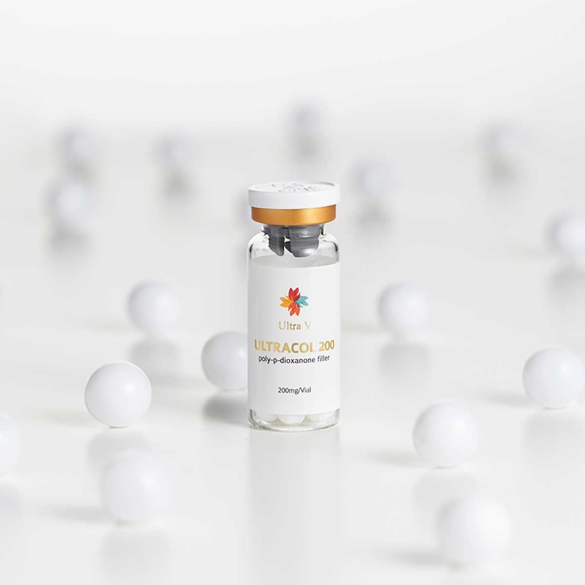 Ultracol cosmetic vial with gold cap on glossy white background surrounded by matte spheres