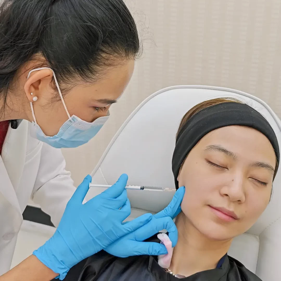 Clinician administering fat-dissolve injection to patients lower cheek and jawline at cosmetic clinic