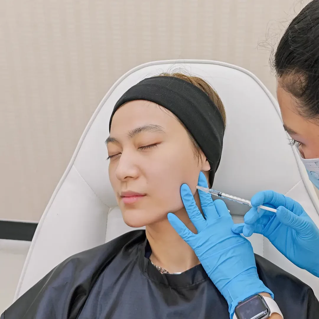 Facial fat grafting procedure in cosmetic clinic, practitioner injecting patients cheek