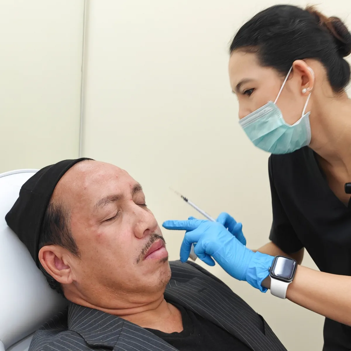 Botox injection to nasolabial fold by masked practitioner in cosmetic clinic