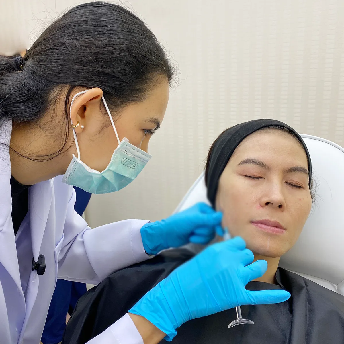 Cheek and temple dermal filler injection by clinician on reclining patient