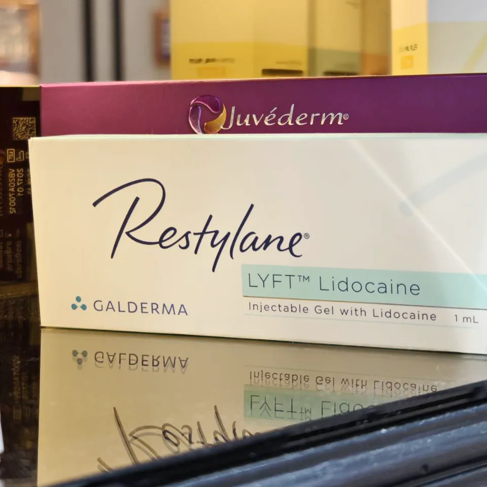 Restylane Lyft Lidocaine dermal filler box with purple Juvéderm packaging reflected on glossy surface