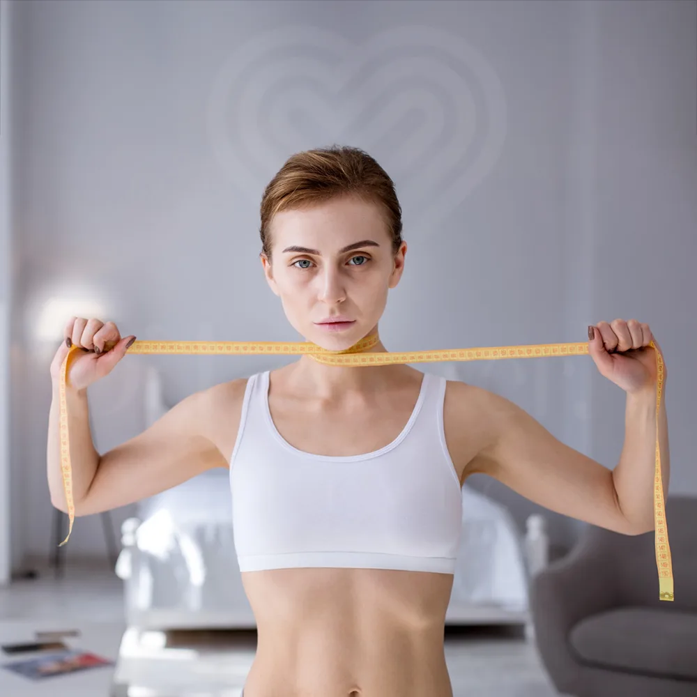 Woman in white sports bra measuring slim face with tape, post weight loss progress