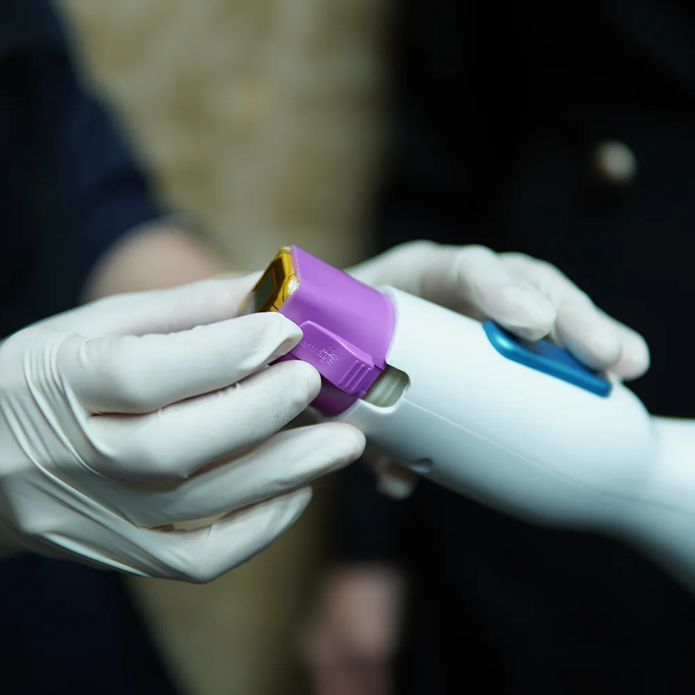 Gloved hands adjusting Thermage neck device with detachable purple head and gold aperture.