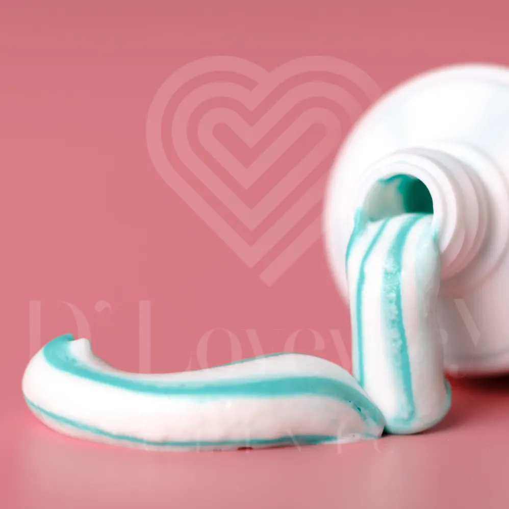Aqua-striped toothpaste tube close-up on pink background