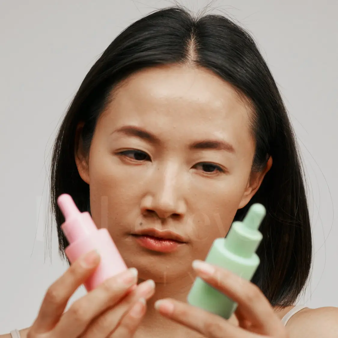 Woman comparing pastel dropper skincare bottles for cosmetic allergy vs steroid allergy