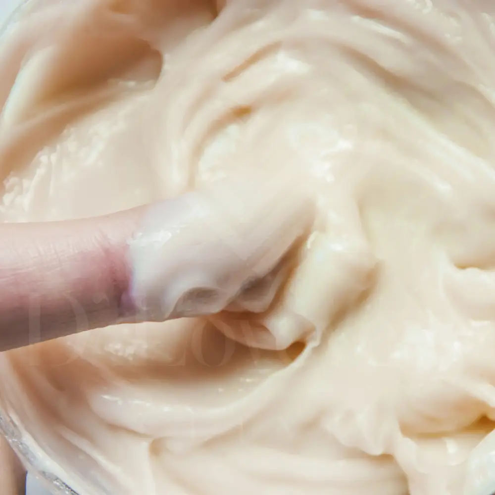 Silky peach-beige face cream moisturizer in jar with fingertip impression, skincare texture