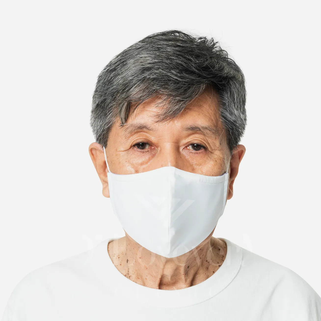 Older adult with droopy eyelids wearing white face mask, studio portrait