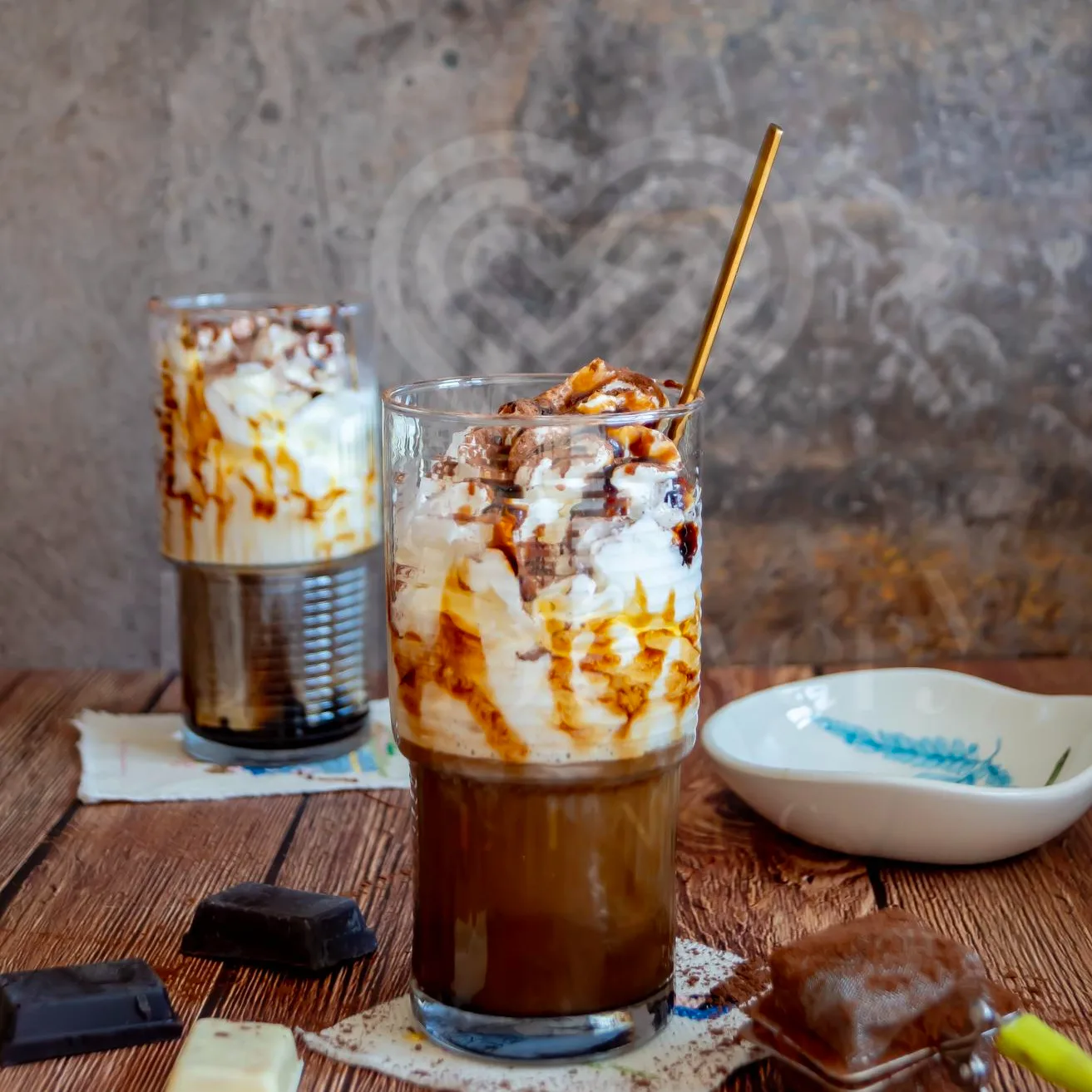 Layered caramel chocolate whipped espresso in tall glass with gold straw