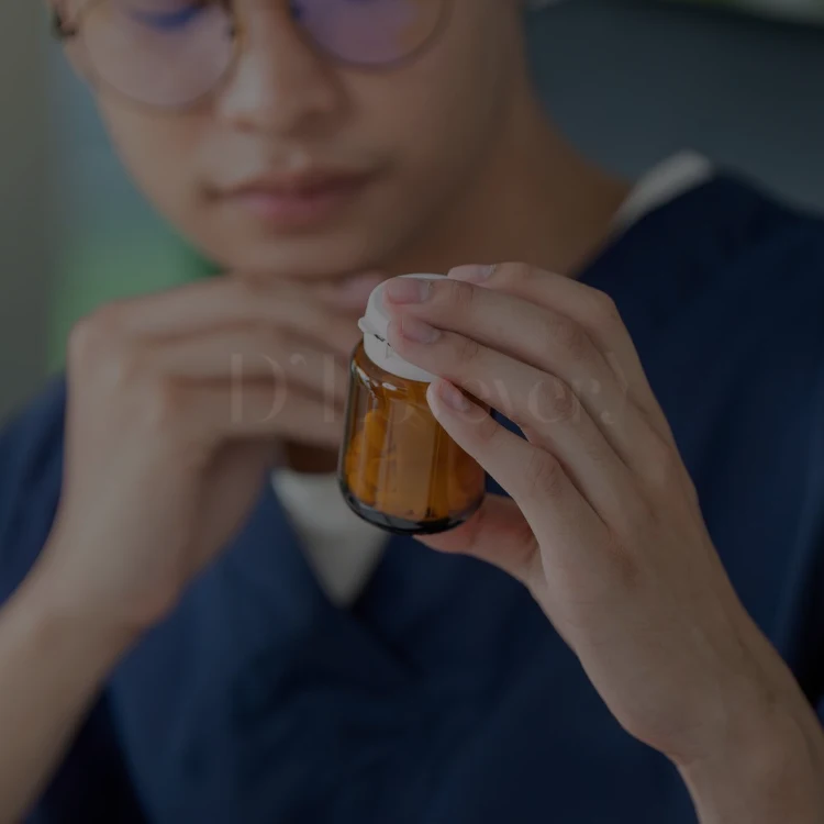Hands holding amber vitamin bottle while person reads supplement label