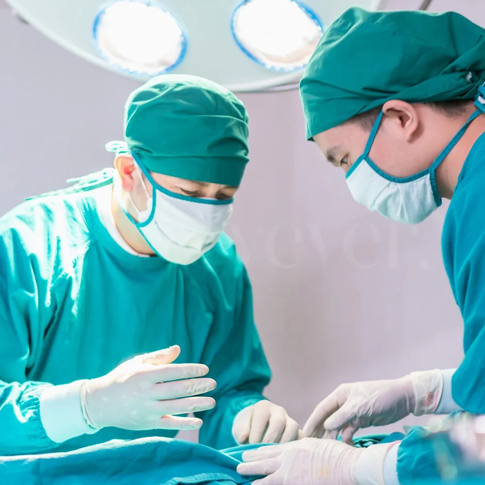 Surgeons performing buccal fat removal in operating room under bright surgical lights