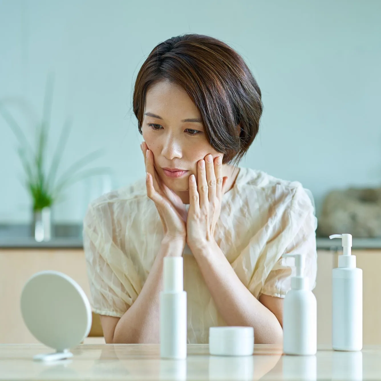 Woman checking skin in mirror with minimalist skincare products